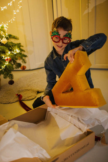 boy opening xmas gift with velvet letter cushion by bettys home