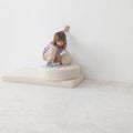 girl standing on boucle mattress with boucle ball in hands, teddy boucle mattress for modern nursery