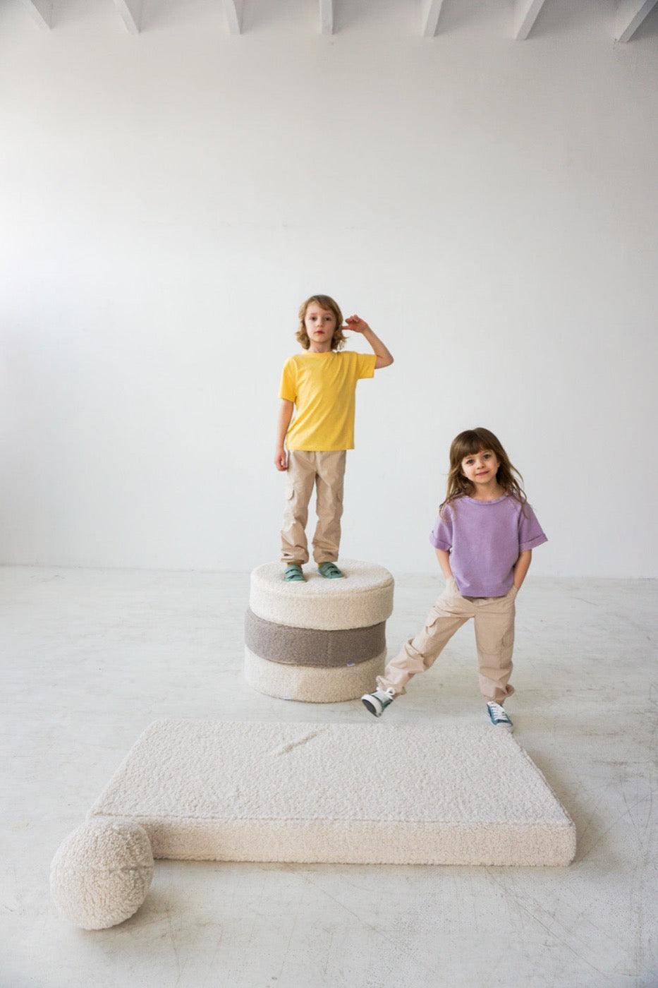 two kids standing on boucle pouf boy bettys home next to boucle mattress