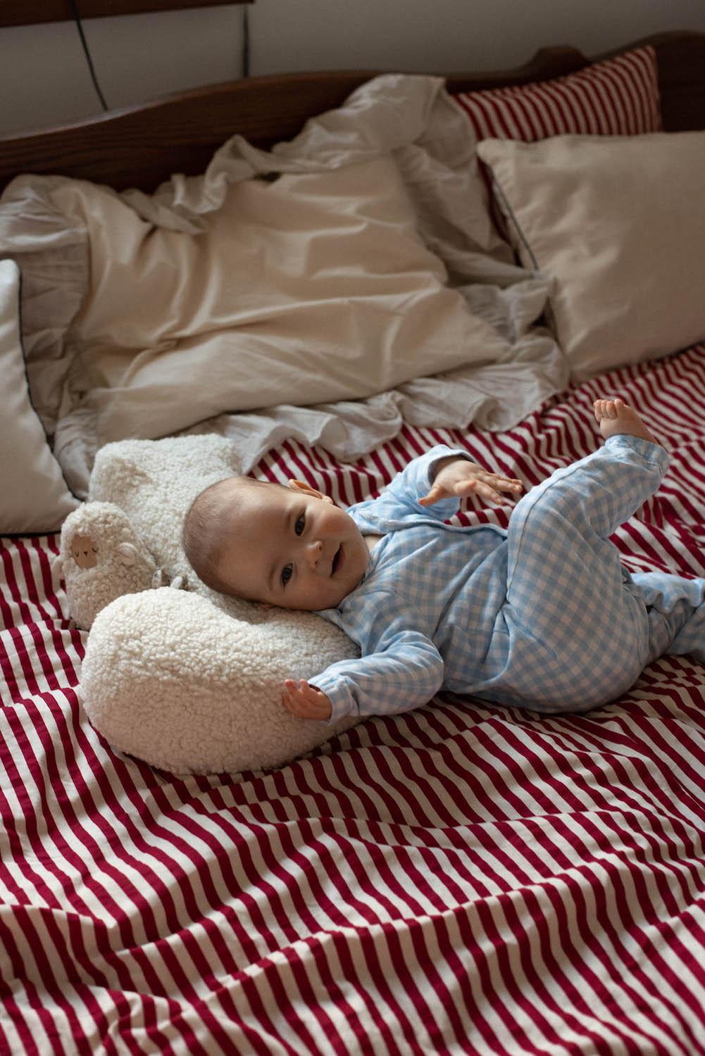 Small child lying on boucle letter pillow by bettys home on bed