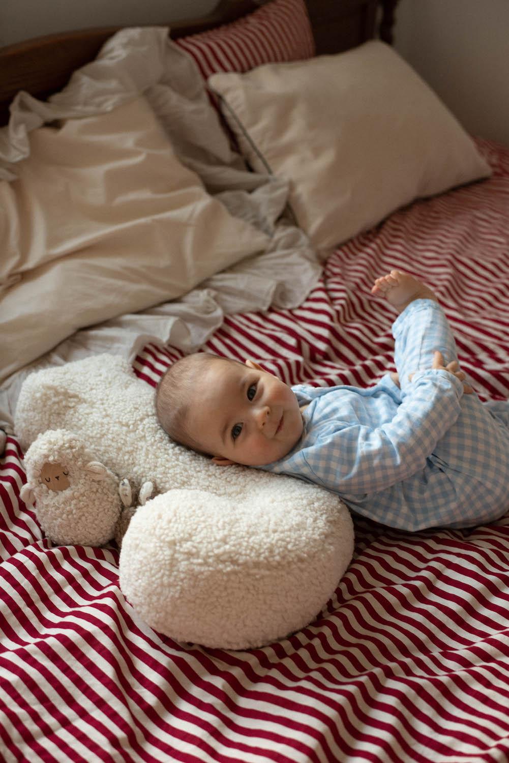 small kid lying on boucle letter pillow J as pillow under head on bed