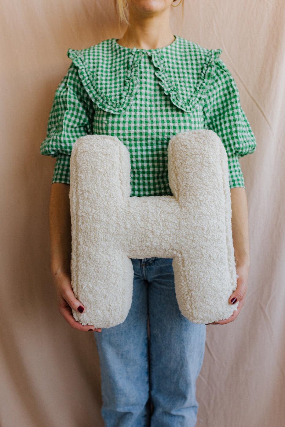 Boucle Letter cushion H by Bettys Home Teddy Letter Pillow held by woman in green checkered t-shirt