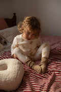 little boy sitting on bed next to boucle pillow y bettys home