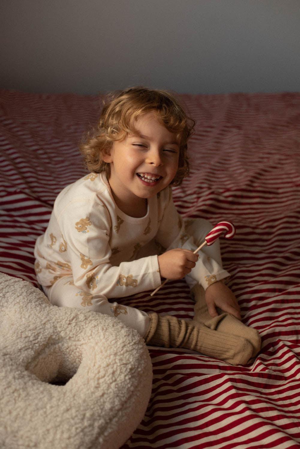 little smiling boy siting on bed in bedroom next to boucle letter cushion B by bettys home