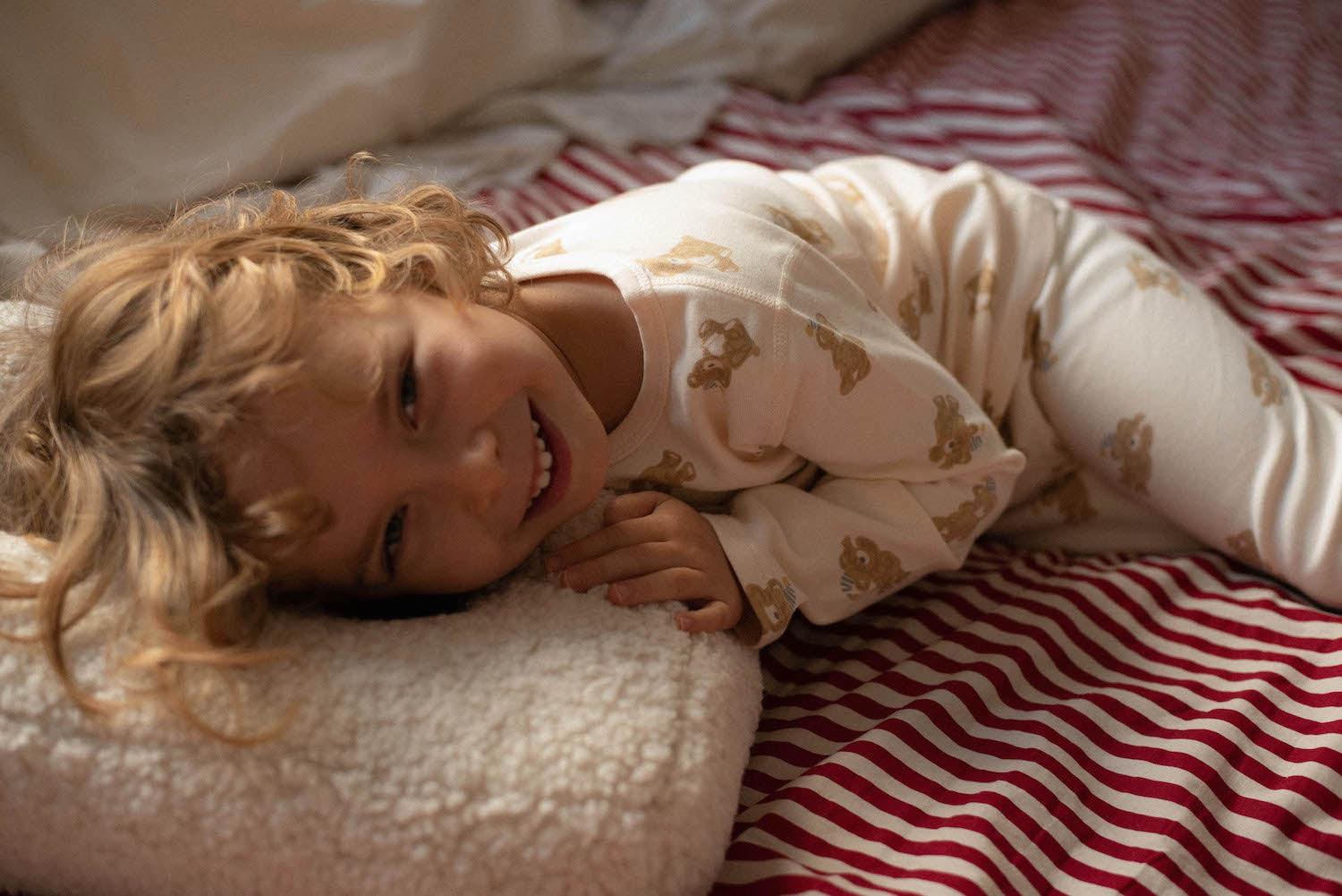 little boy lying on boucle cushion by bettys home on bed