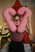 Christmas candy cane cushion red stripes by bettys home which is held by a girl by placing it on both sides of her head