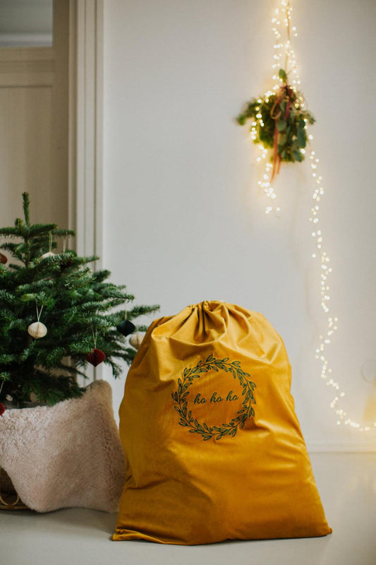 christmas sack in yellow with embroidered ho ho ho by Bettys Home next to christmas tree. Yellow Santa Sack