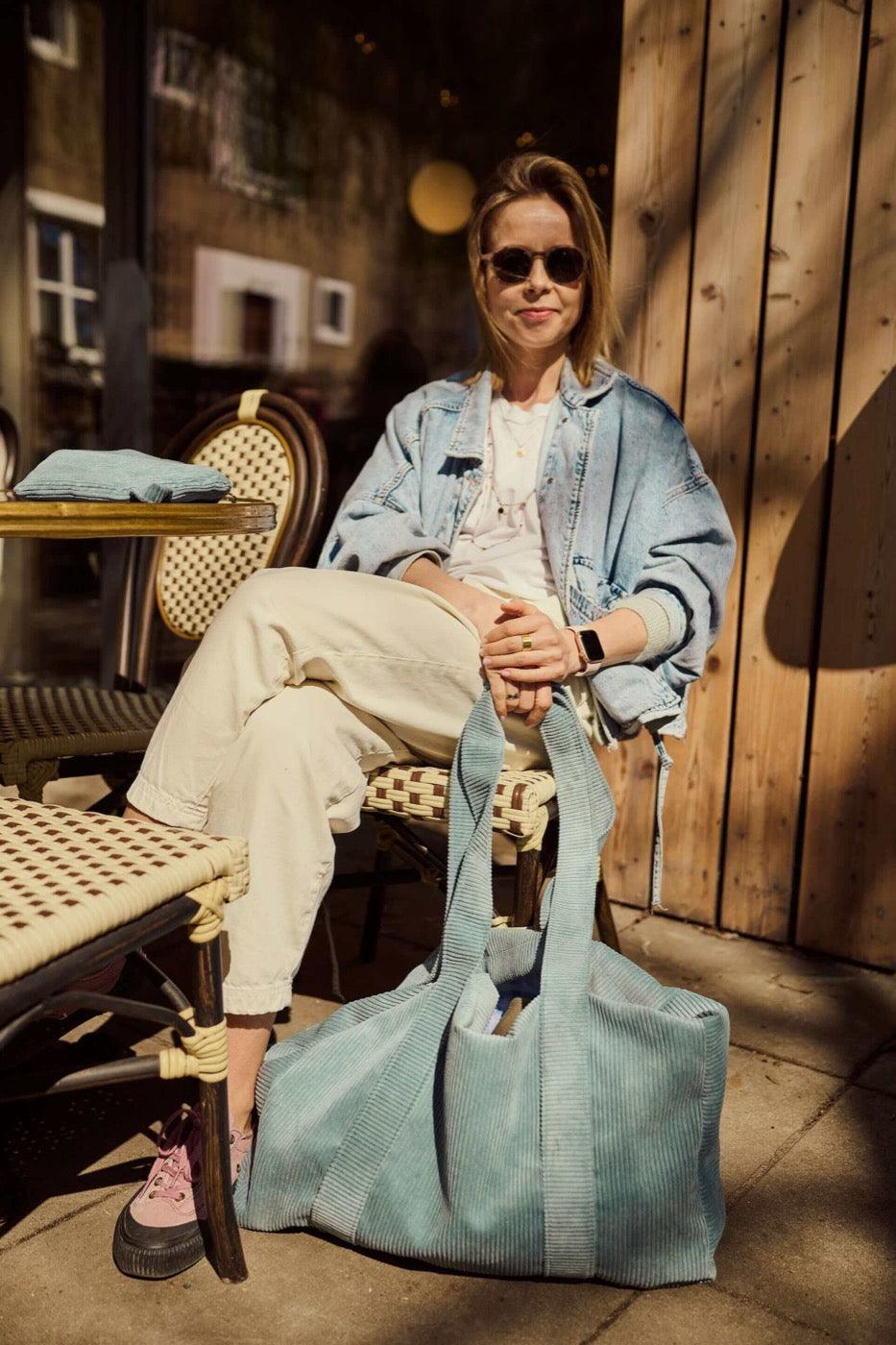 A girl during her free time siting in restaurant with corduroy blue tote bag by bettys home