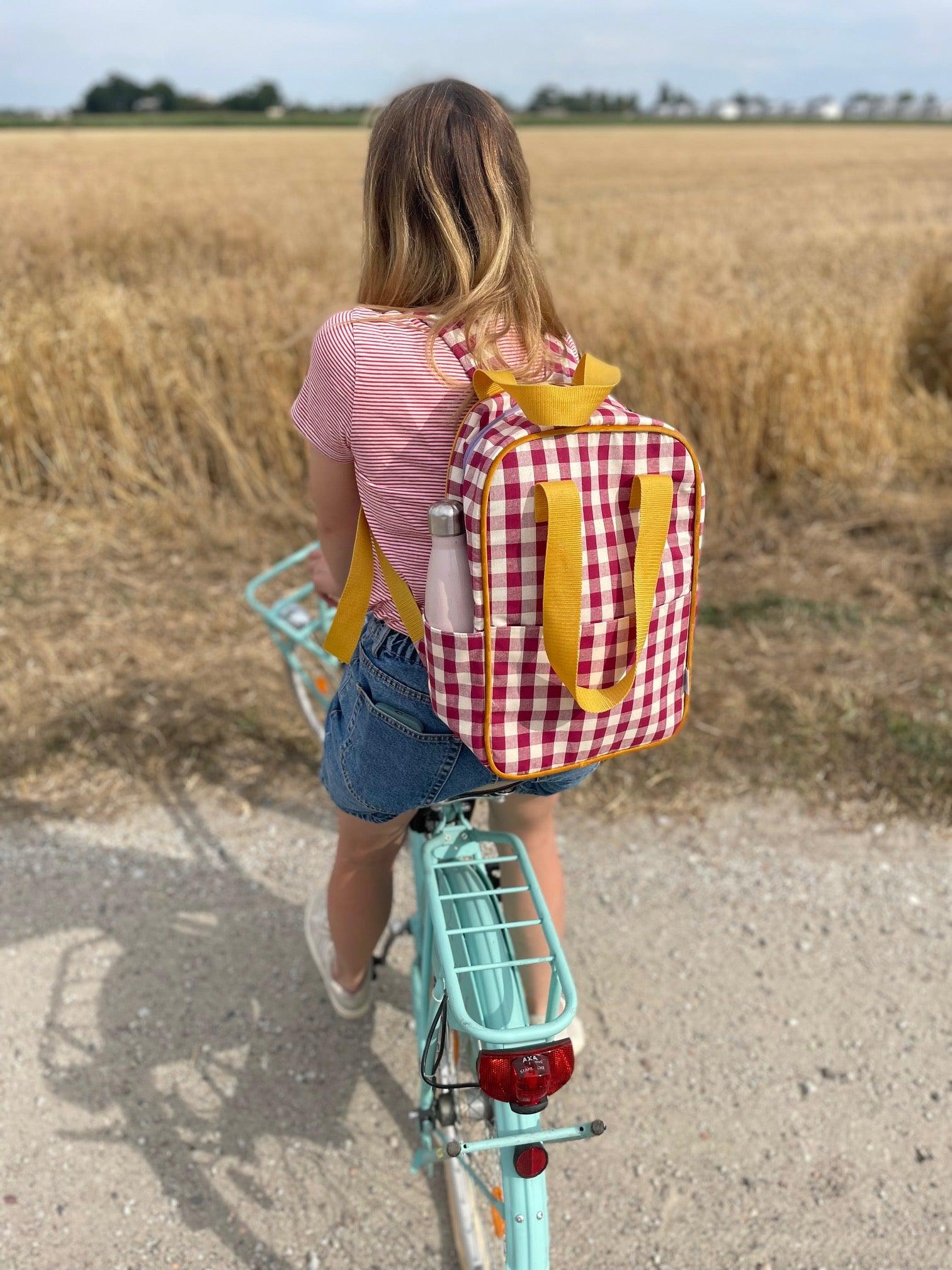 girl on mint bike with red checkered backpack by bettys home on trip