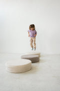 little girl jumping on floor boucle floor pouf by bettys home