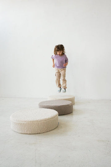 little girl jumping on floor boucle floor pouf by bettys home