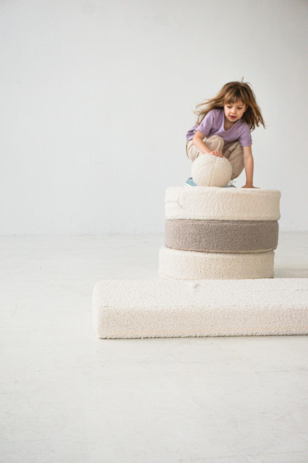 girl jumping on boucle floor pouf by bettys home with boucle ball cushion