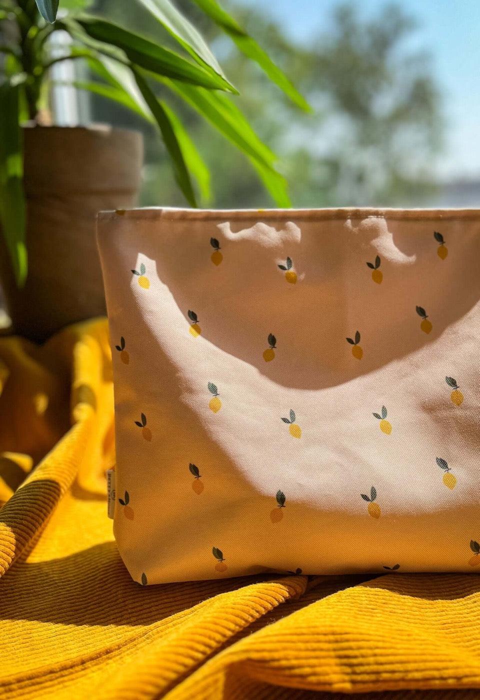 Cosmetic bag in lemons for the beach. Inside the cosmetic bag are children's wet bathing suits and sunscreen. Holiday essentials from Bettys Home