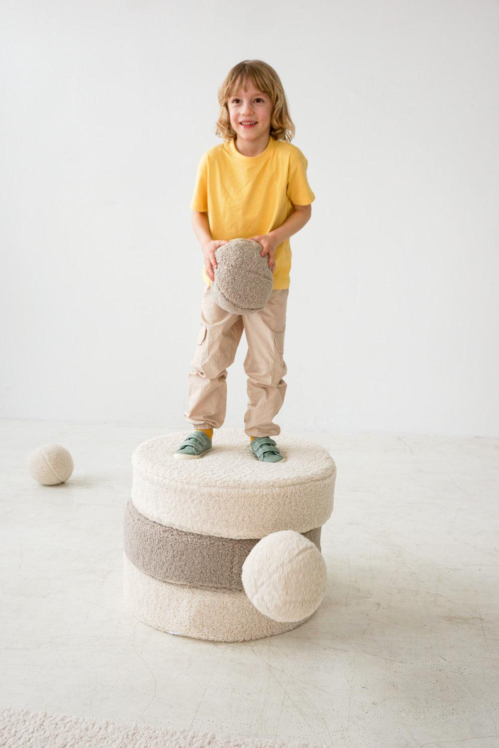little boy standing on boucle large pouf by bettys home with boucle ball cushion