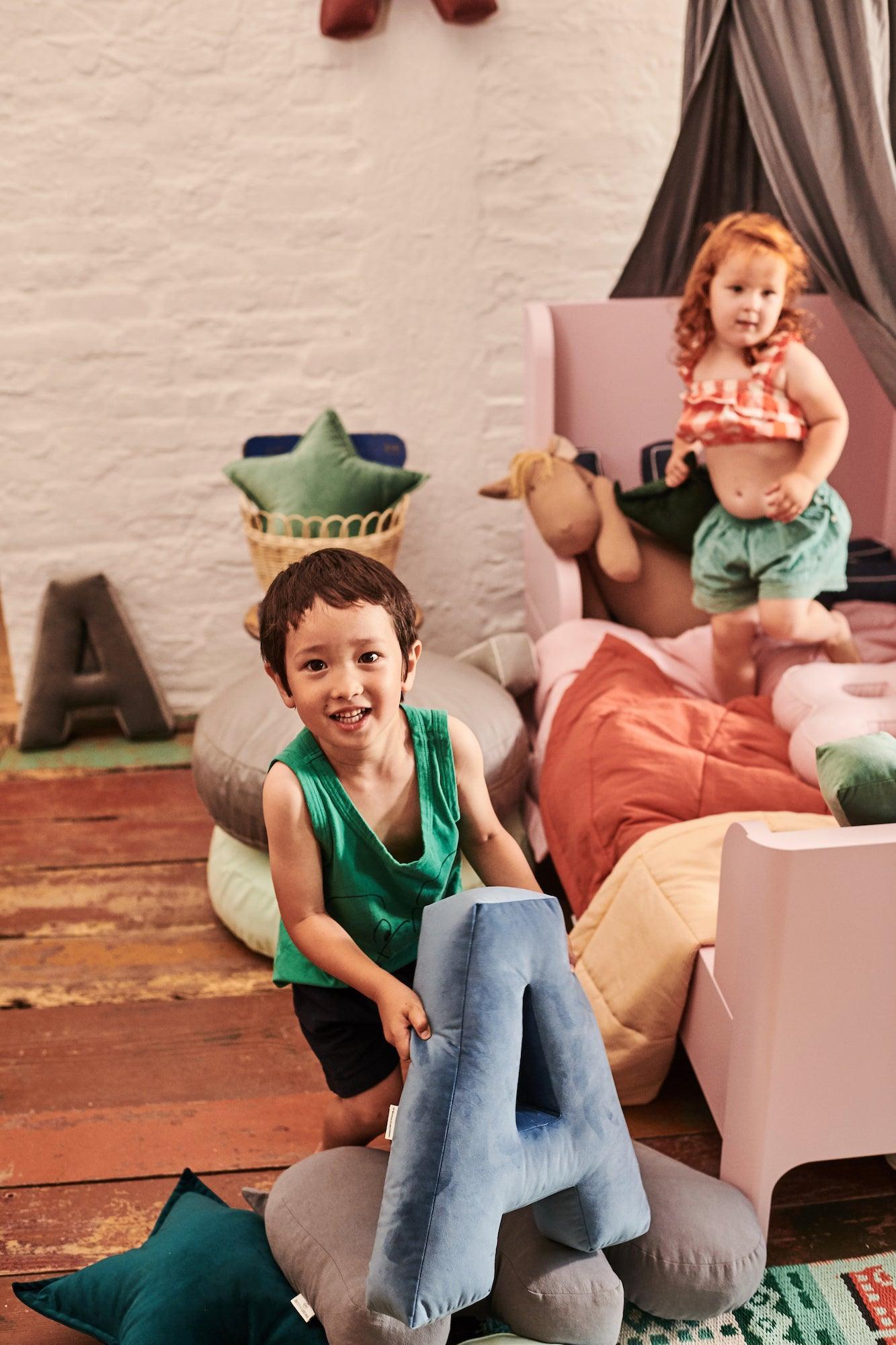 little kids in kindergarten playing with Velvet letter cushions by Bettys Home