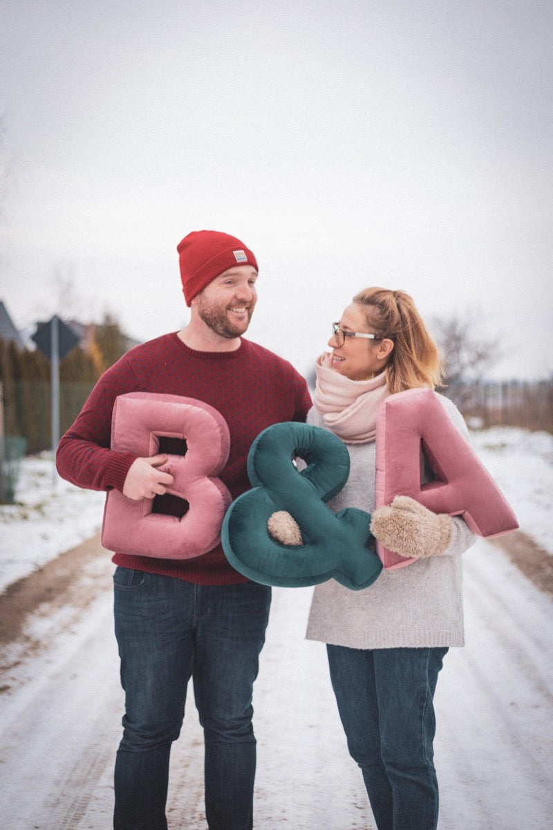 A couple in a winter landscape holds velvet letter cushion. Xmas gift idea for couples. Xmas gift idea for her