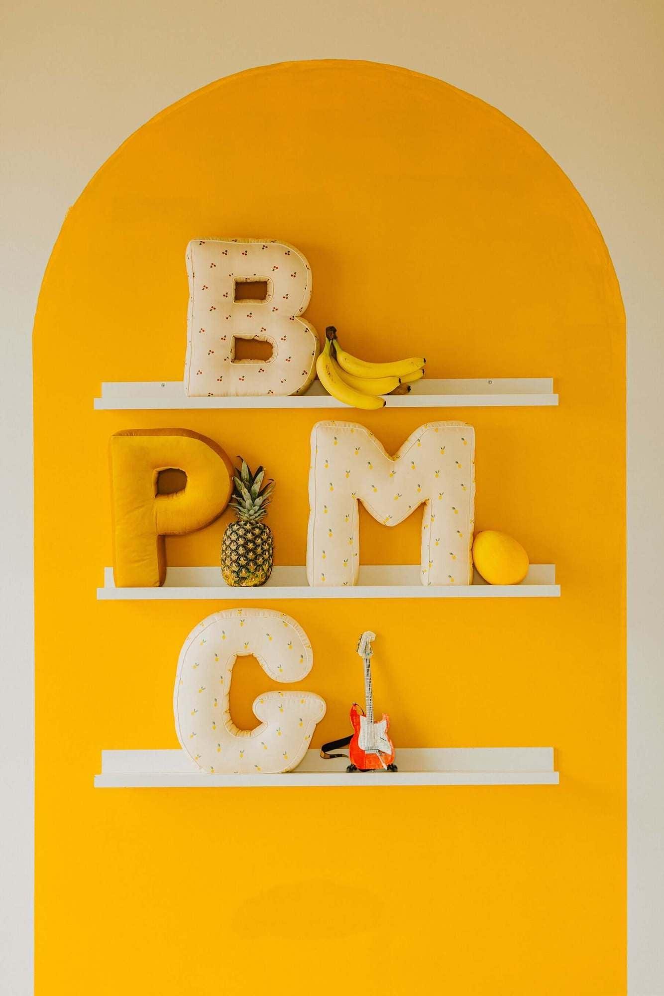 pillows letter shaped by bettys home on shelf on the yellow wall