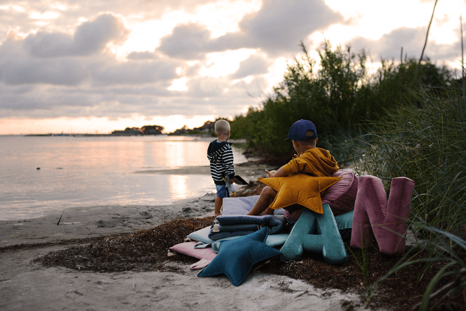 beach view with velvet star cushions and velvet letter cushions on sand by bettys home