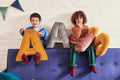 two young boys sitting on sofa with velvet letter shaped cushions a and s in yellow by bettys home
