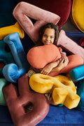 cute girl under lot of velvet letter cushions and cotton hippo pillow by bettys home