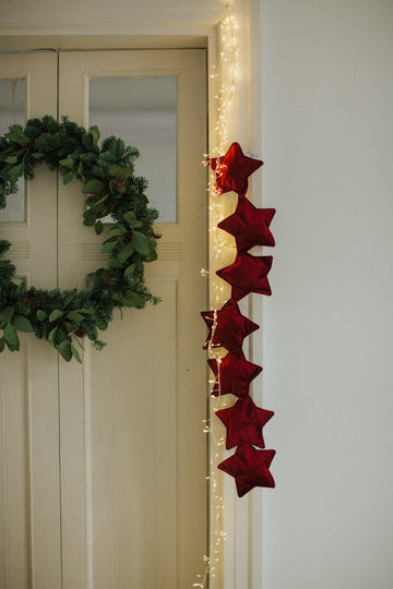 velvet star garland wine red by bettys home hanging on the door as a Christmas decoration