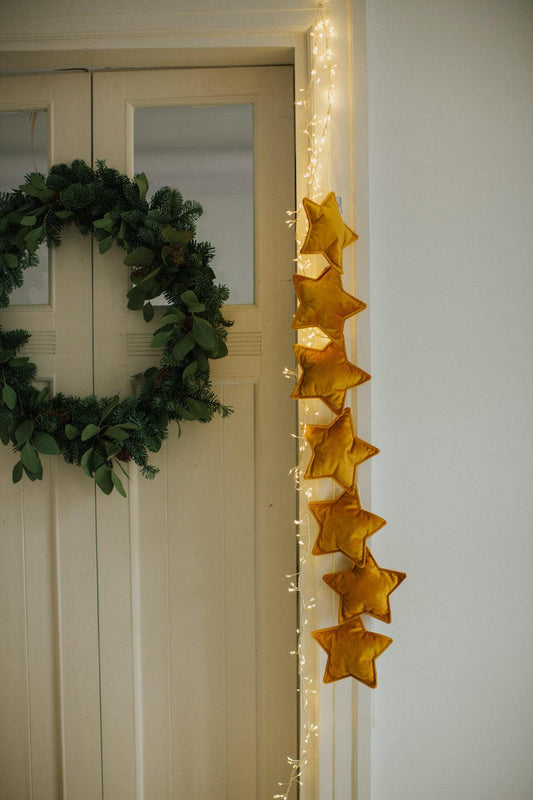 velvet star garland yellow by bettys home hanging on the door as a festive decoration