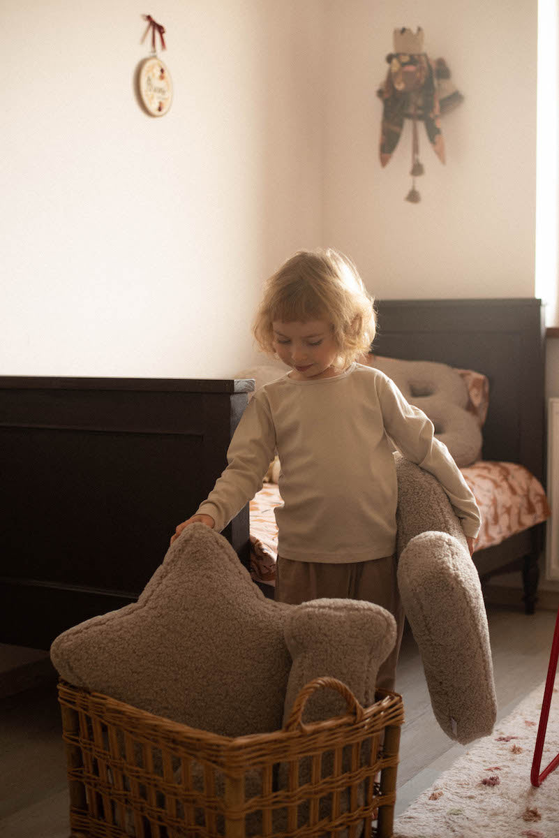 boucle star cushion mocha in wicker cart and little boy. teddy pillow