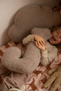 little boy lying and laughing on bed with boucle letter cushion J mocha
