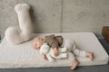 little boy lying on a boucle mattress next to a cream boucle letter cushion from bettys home, teddy boucle mattress for modern nursery