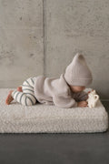 a small child lying on a boucle mattress on the floor while playing. boucle floor mattress from bettys home, teddy boucle mattress for modern nursery