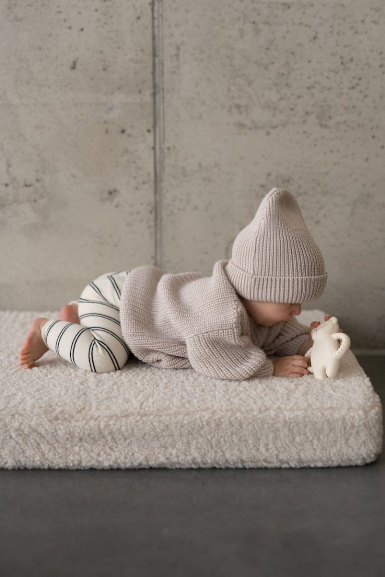 a small child lying on a boucle mattress on the floor while playing. boucle floor mattress from bettys home, teddy boucle mattress for modern nursery