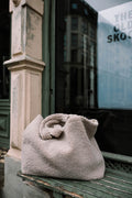 boucle shopper bag by bettys home lying on bench in front of shop window. boucle tote bag