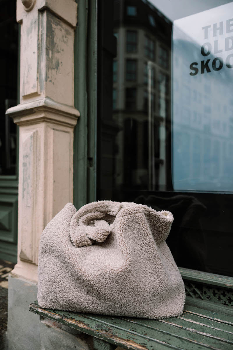 boucle shopper bag by bettys home lying on bench in front of shop window. boucle tote bag