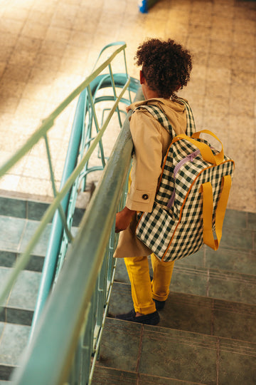 a boy at school after lesson with gingham backpack by bettys home