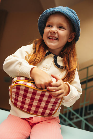 smilling girl with gingham belt bag in reed by bettys home. Fanny pack gingham