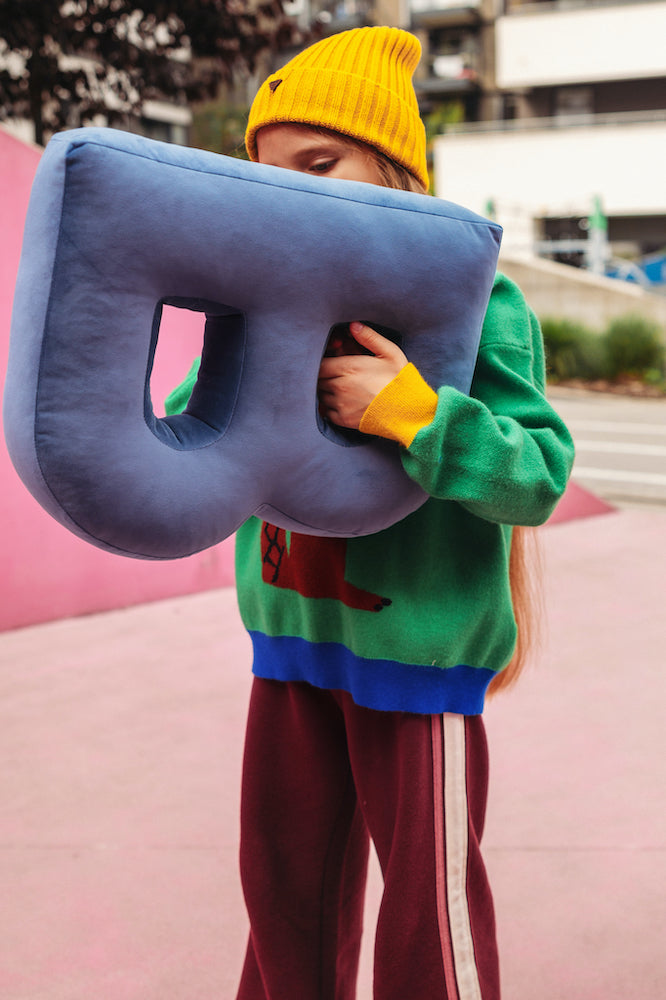 girl with velvet letter cushion b in blue in her hands. letter shaped pillows