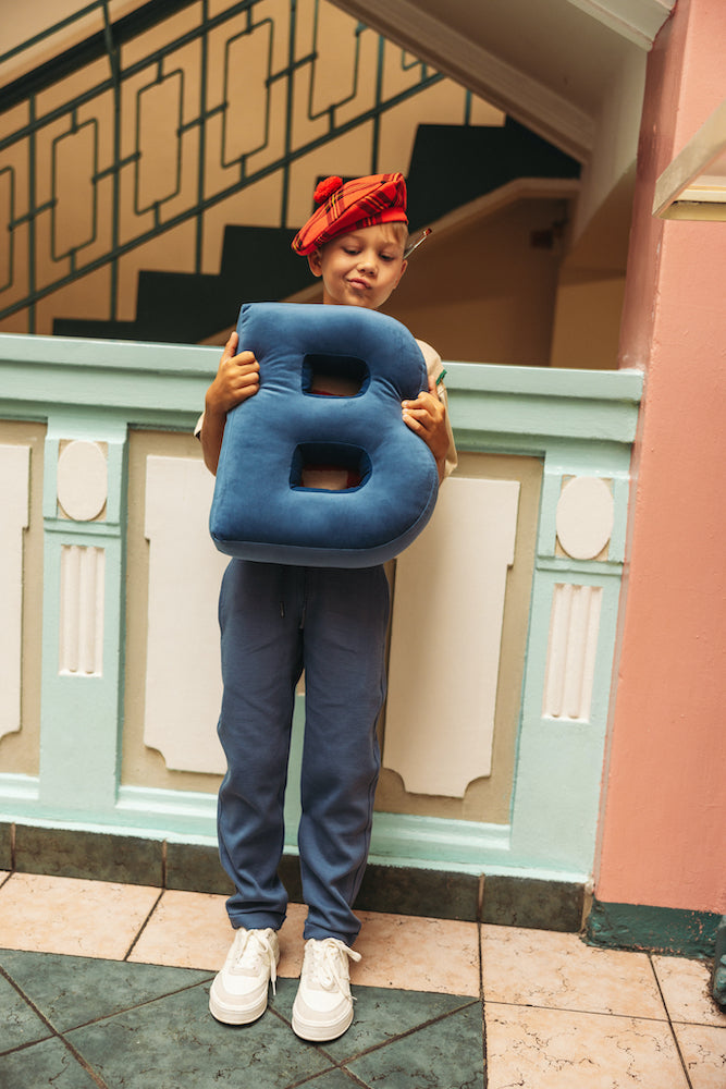 boy at school holding velvet letter cushion b by bettys home. letter shaped cushion
