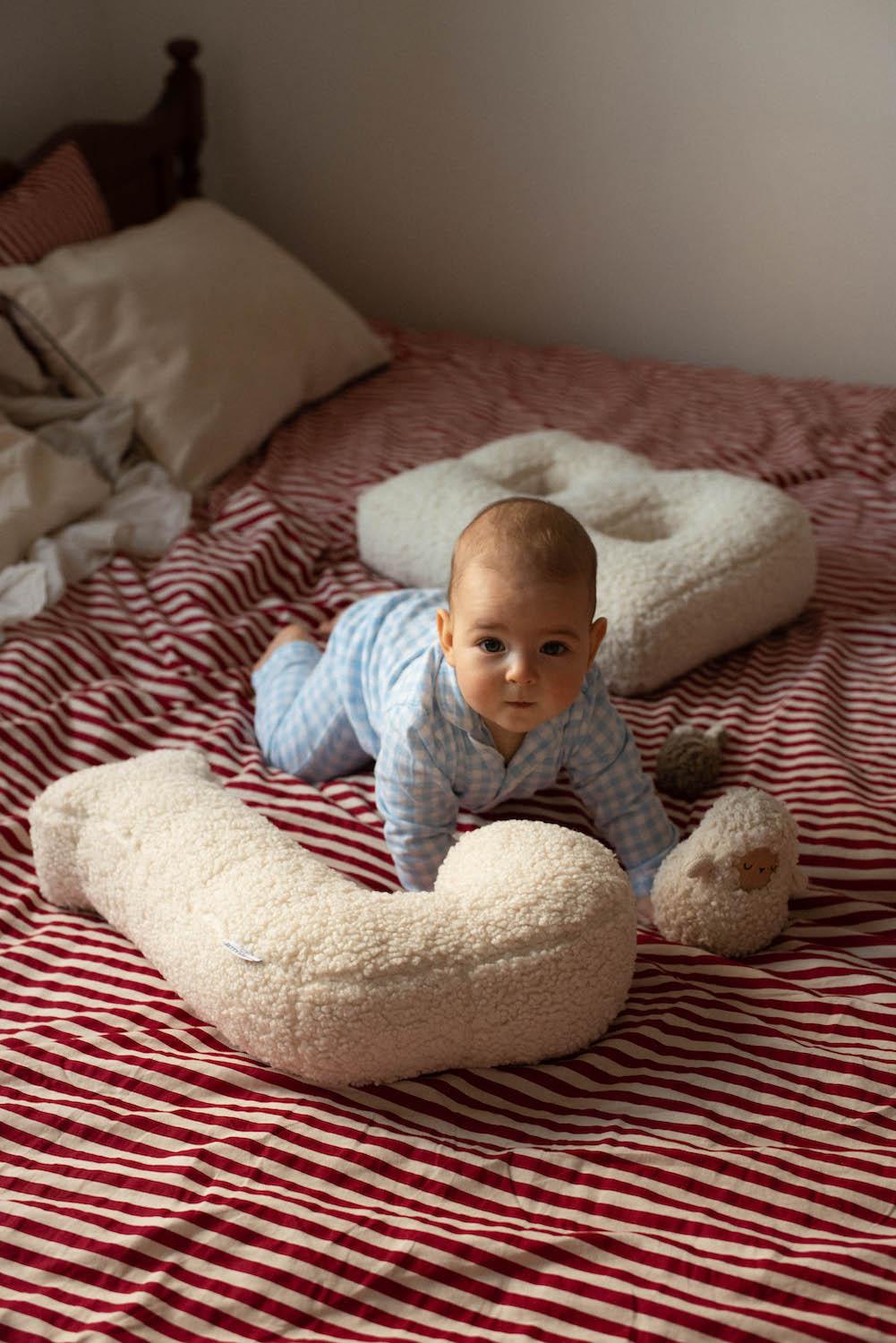 baby boy lying on bed next to teddy pillow in shape of letter J and B by bettys home