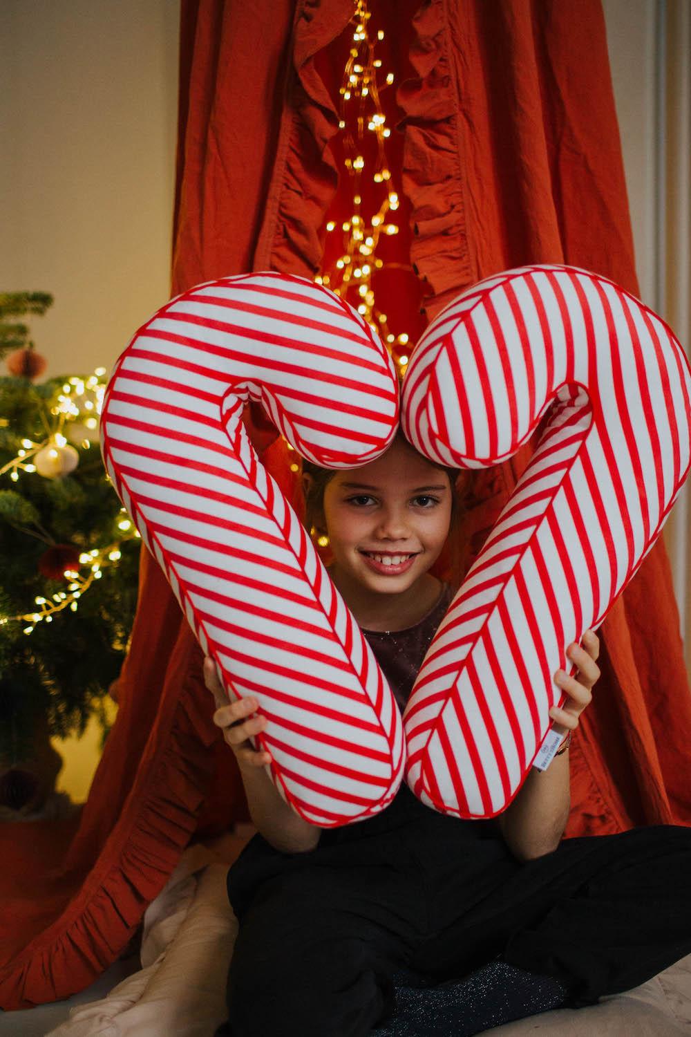 Christmas candy cane cushion red stripes by bettys home held in front of her by a little girl. Candy Cane Pillow Pottery Barn