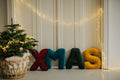 Velvet Letter cushions by Bettys Home arranged in the word XMAS next to christmas tree.