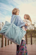Happy mom with her daughter. Mom is holding her kids and she has blue mom bag by bettys home. 
