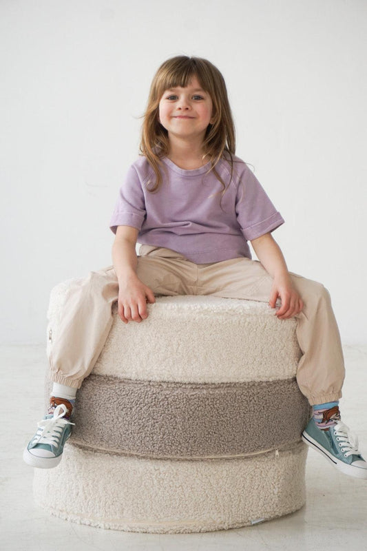 girl sitting on large boucle pouf by bettys home in taupe colour 