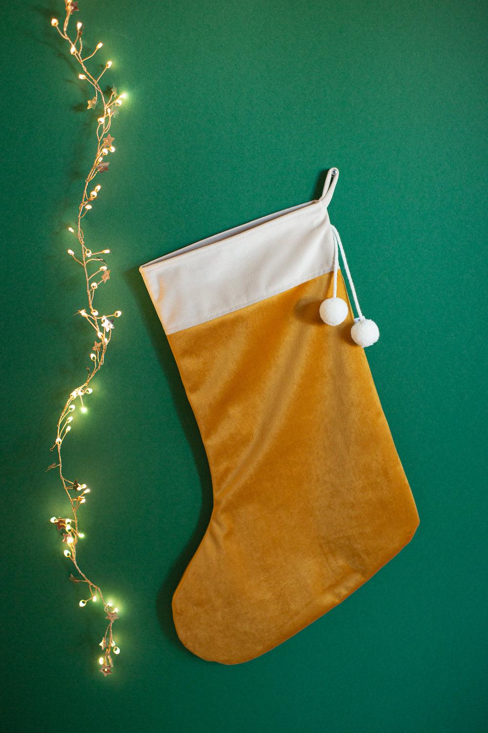 christmas stocking in yellow velvet by bettys home hanging on green wall as traditional christmas decoration ideas