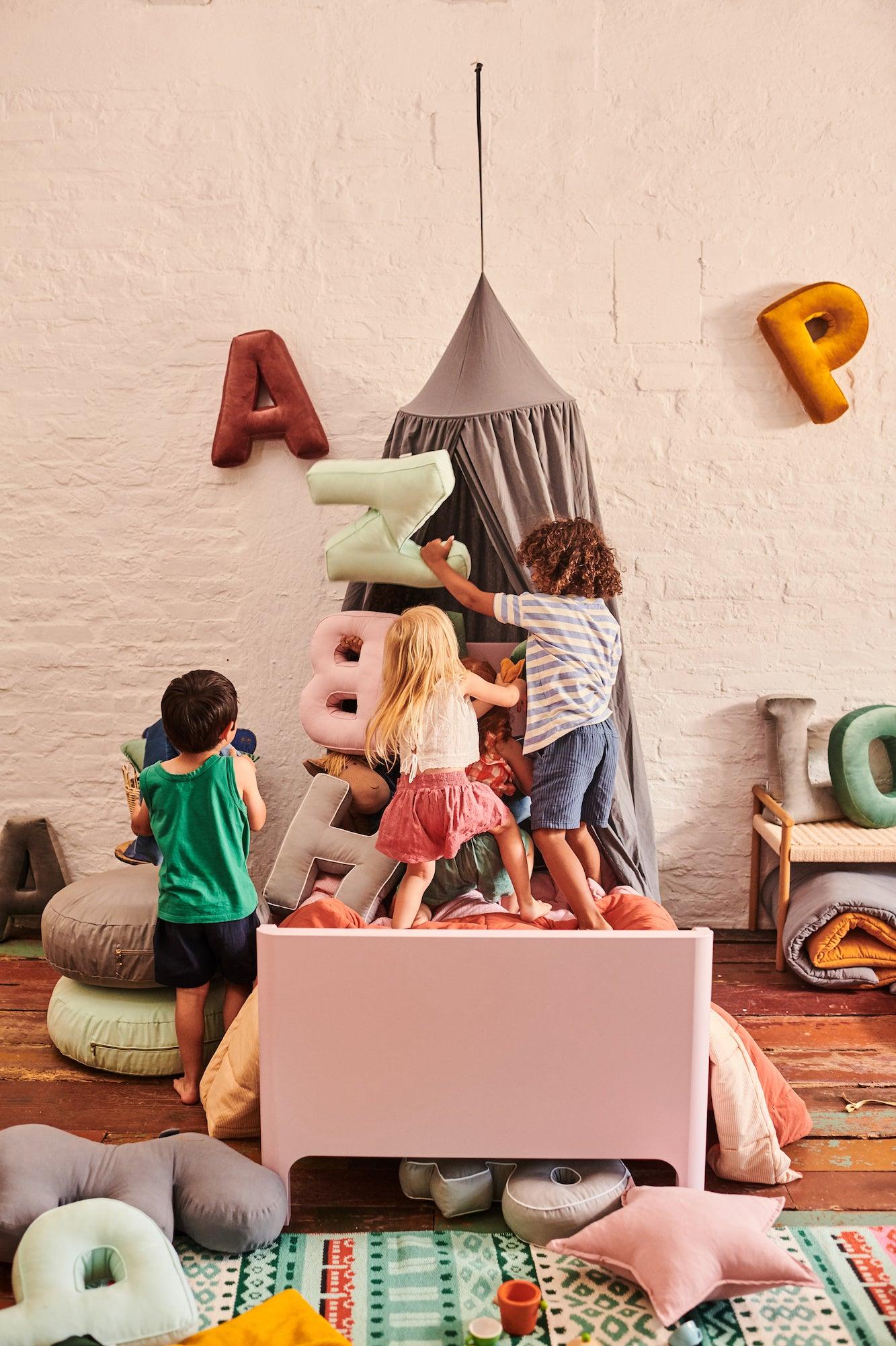 Beautiful room with kids room decorations. Above the bed is a canopy and several happy children. How do you style a twin room.