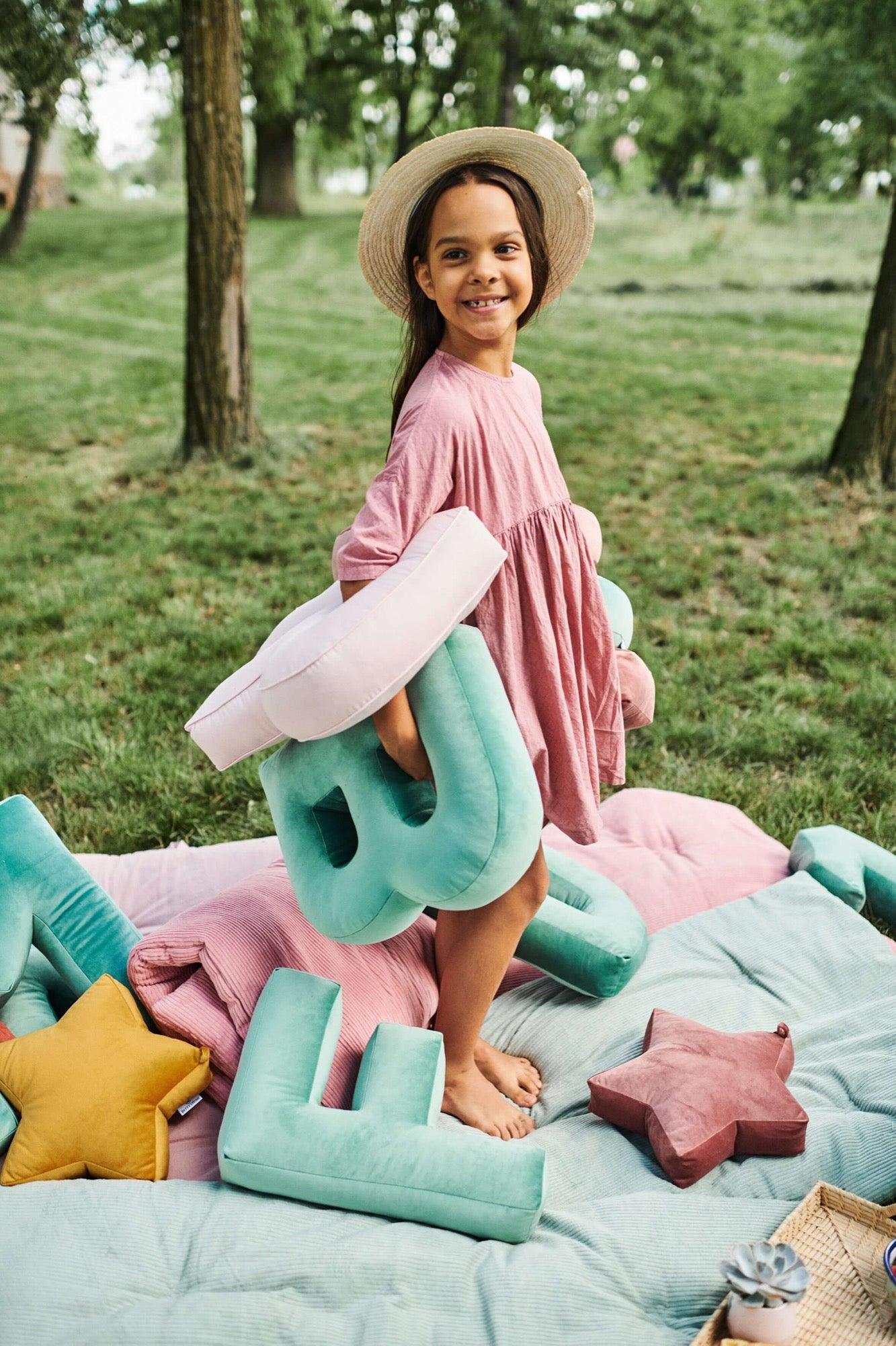 girl in garden holding velvet letter pillow b in mint by bettys home which is great birthday gifts for twins girl 