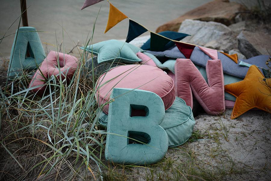 letter pillow b mint by bettys home on beach and sea behind 