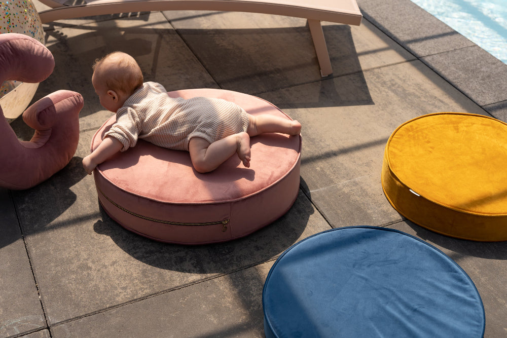 little boy on large velvet pouf in garden next to velvet letter cushion by bettys home