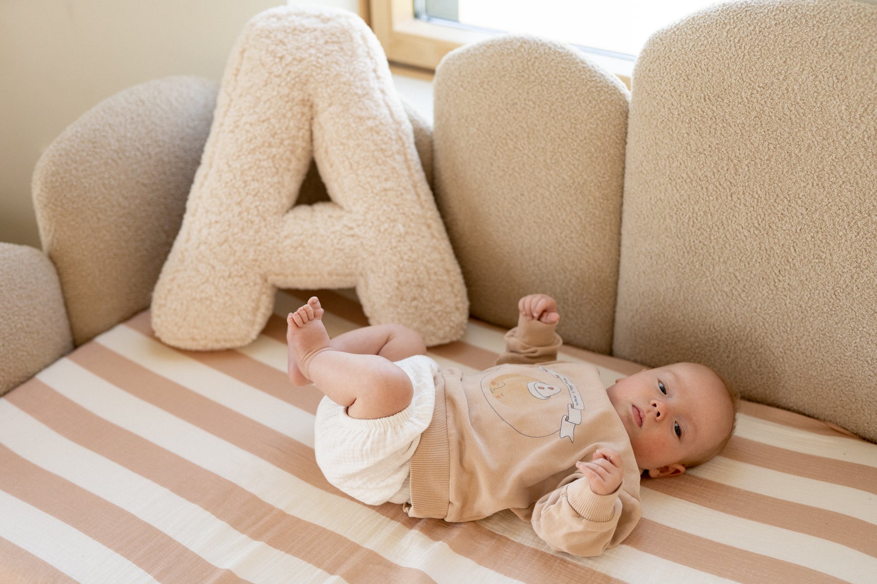 children on a bed near to A boucle letter cushion by betty's home. Newborn gift idea