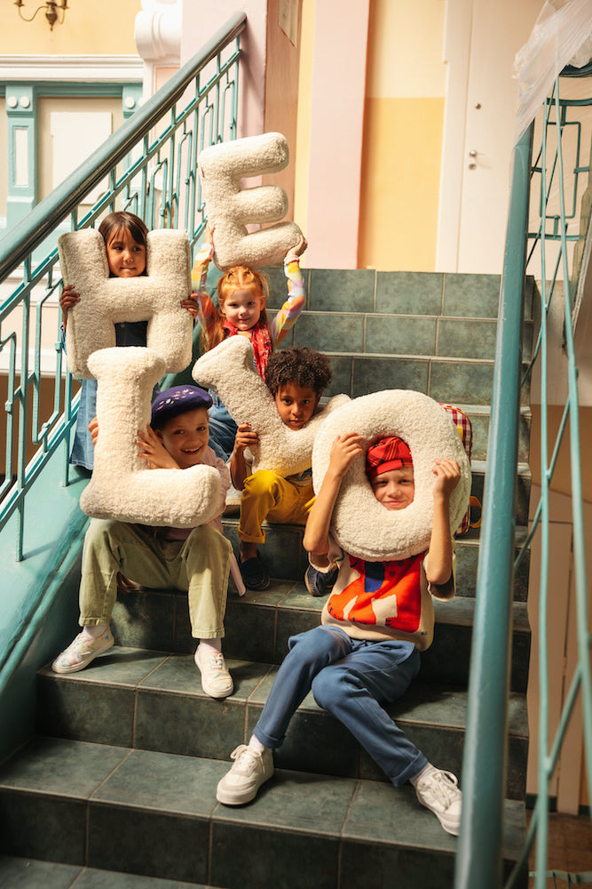 kids at school sitting on stairs with boucle letter cushions baby bettys home. Letter shaped teddy cushions