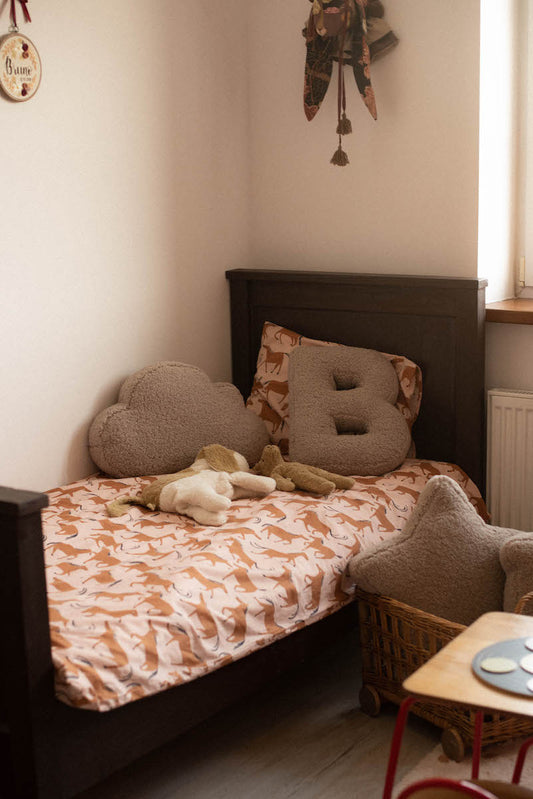 cloud cushion boucle lying on bed next to boucle letter cushion B by bettys home